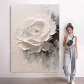 Woman standing next to a large abstract painting of a white flower