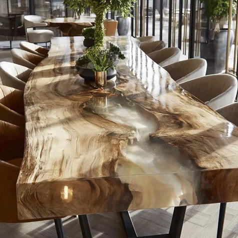 A large live-edge wooden dining table with a glossy resin-like top showing natural wood grain and flowing patterns, surrounded by upholstered chairs in a modern dining room.