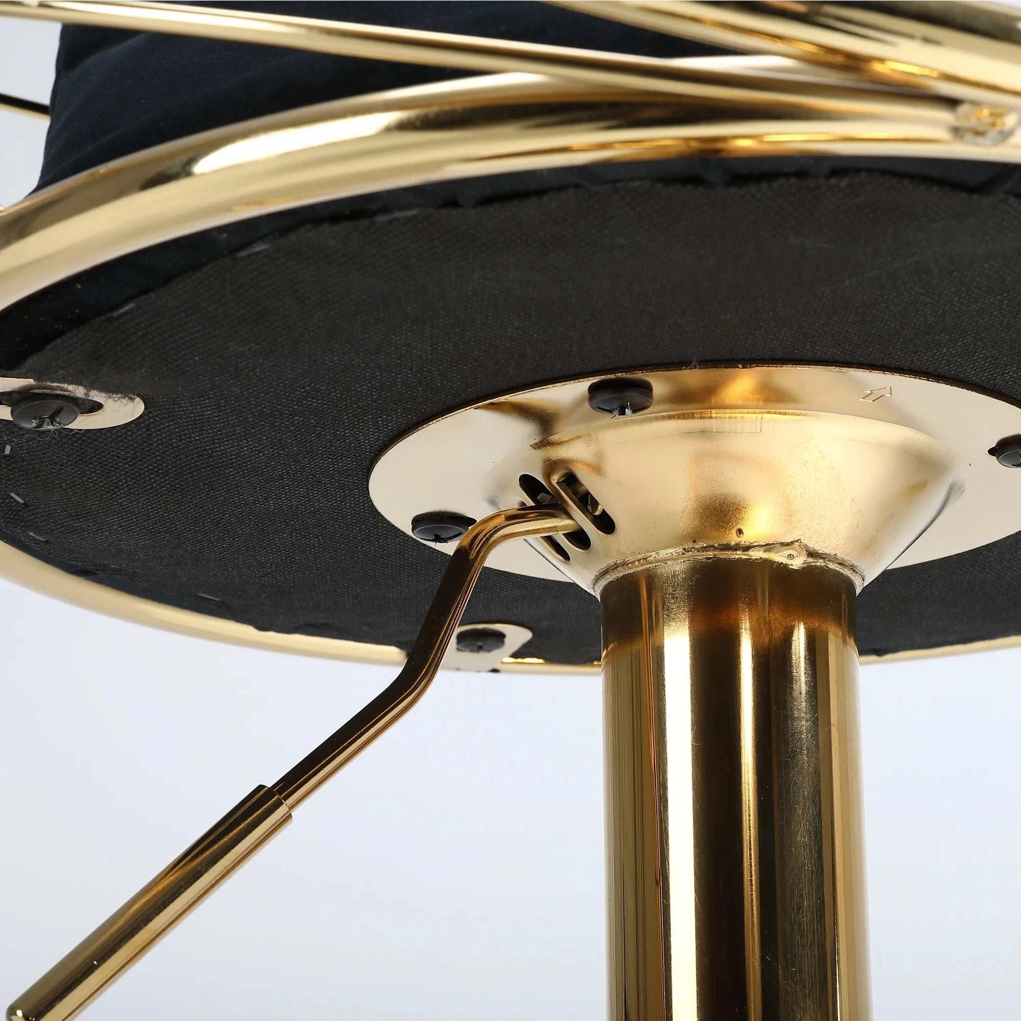 Close-up of a chair with gold metal base and black cushion on a white background