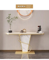 Decorative console table with marble base and gold accents against a striped wall.