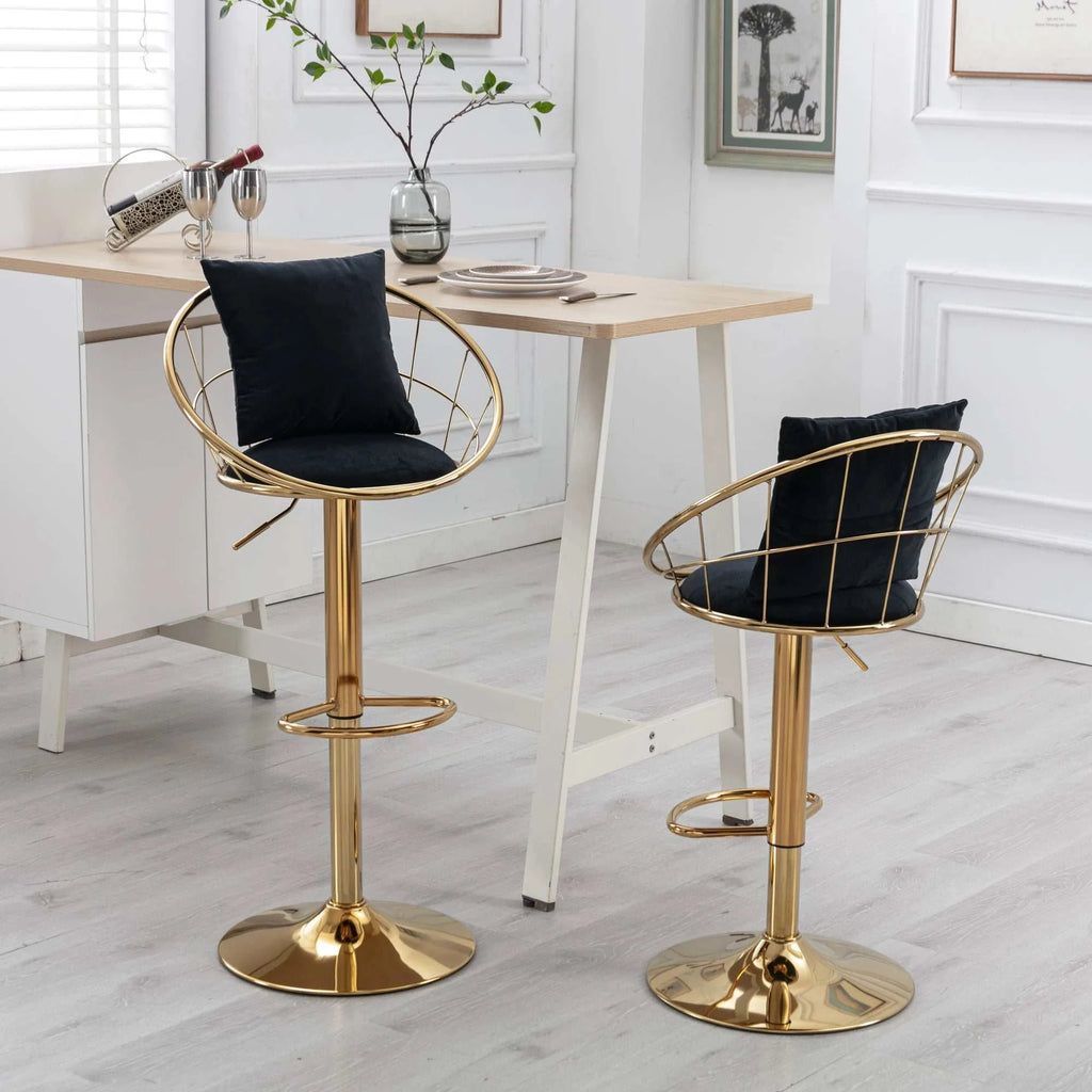 Two gold bar stools with black cushions in a room with a table and decor.
