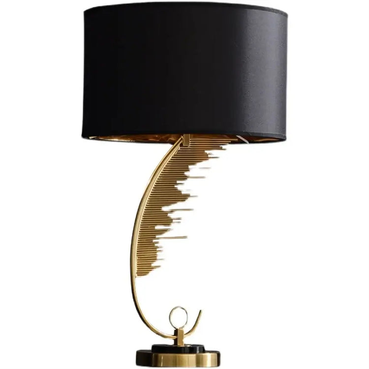 Decorative table lamp with black shade and gold base on a white background