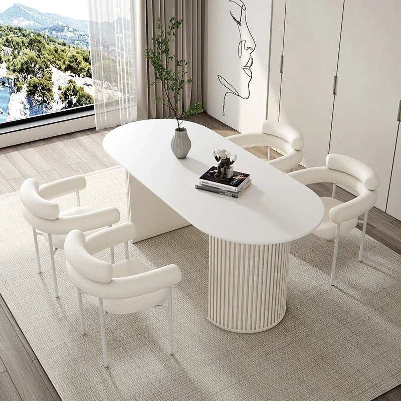 Modern dining room with a white oval table and chairs, featuring a scenic view through large windows.
