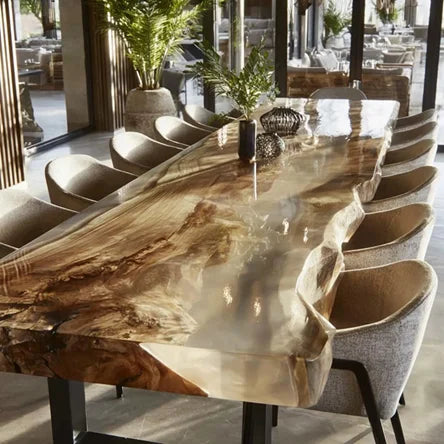 A large live-edge wooden dining table with a glossy polished resin top, surrounded by modern upholstered dining chairs in a bright, contemporary dining room.