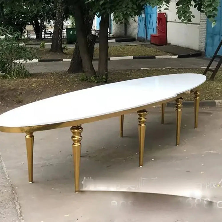 Long white table with gold legs on a concrete surface, outdoor setting
