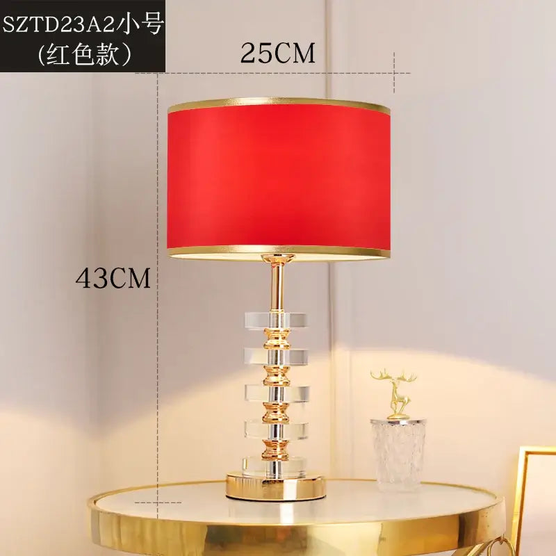 Modern crystal table lamp with fabric shade featuring a red shade and gold accents on a clear crystal base.