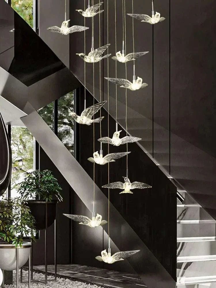 Modern loft chandelier with LED lighting and acrylic bird pendants hanging in stylish staircase interior