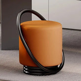 Orange cylindrical stool with black curved handle on a textured floor.