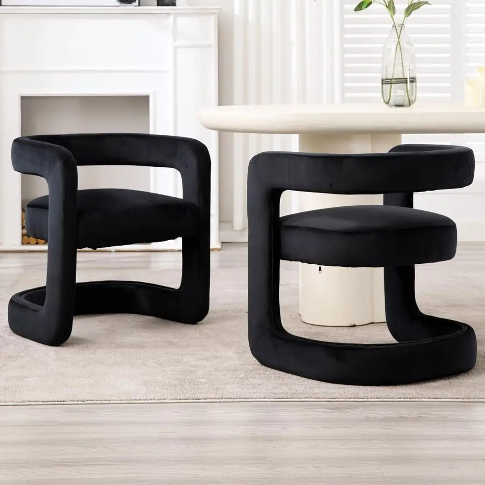 Two black modern chairs in a room with a fireplace and table.
