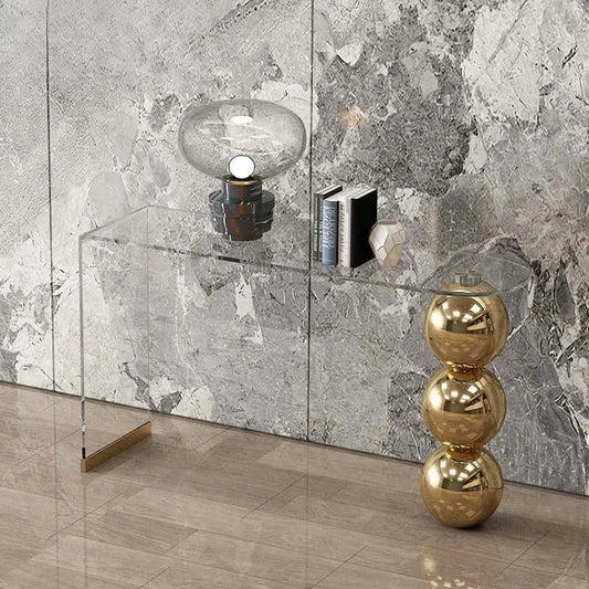Modern interior design with a glass console table against a marble wall.