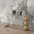 Modern interior design with a glass console table against a marble wall.