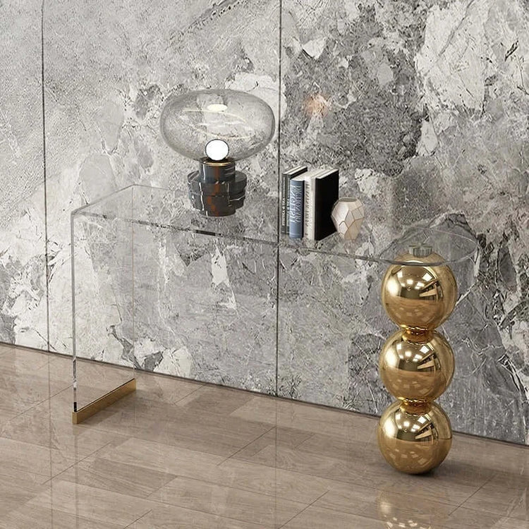 Modern interior design with a glass console table against a marble wall.