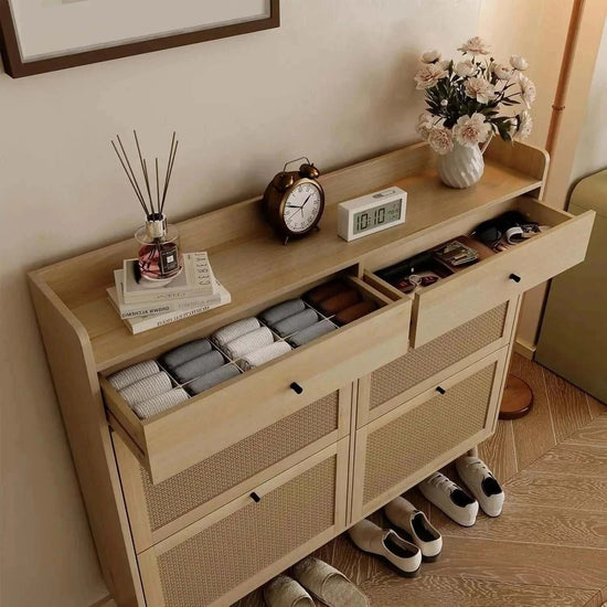 Stylish rattan shoe cabinet with spacious drawers, decor items, and beautiful flower arrangement.