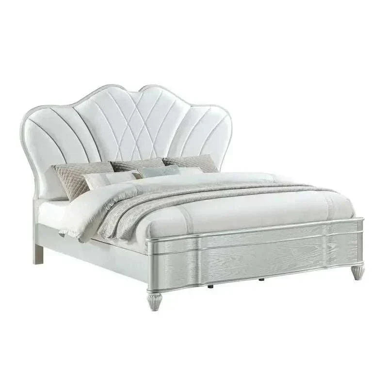 White upholstered bed with decorative headboard on a white background
