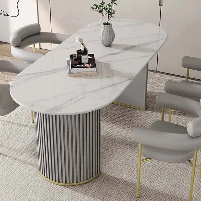 Modern dining table with marble top and cylindrical base in a room setting.