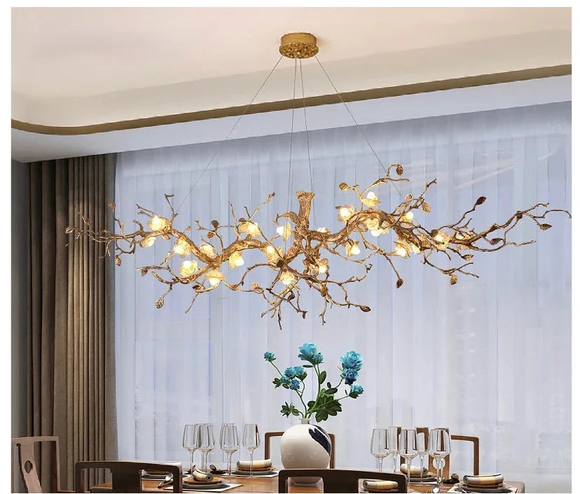 Gold chandelier hanging above a dining table with a vase of flowers on a neutral background