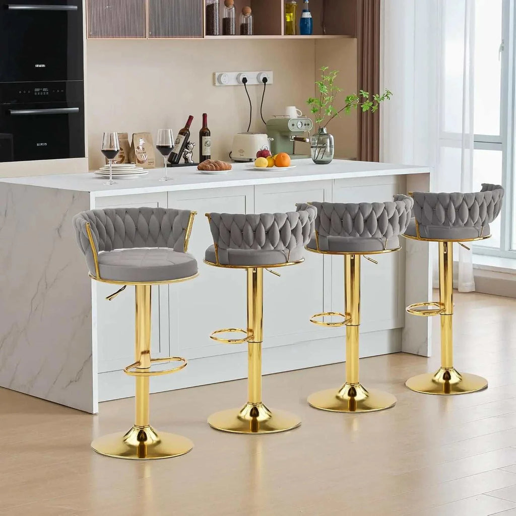 Four gray bar stools with gold legs in a kitchen setting.