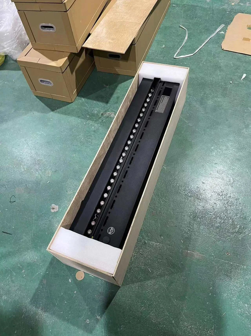 Electronic device in a box on a green floor with cardboard boxes in the background