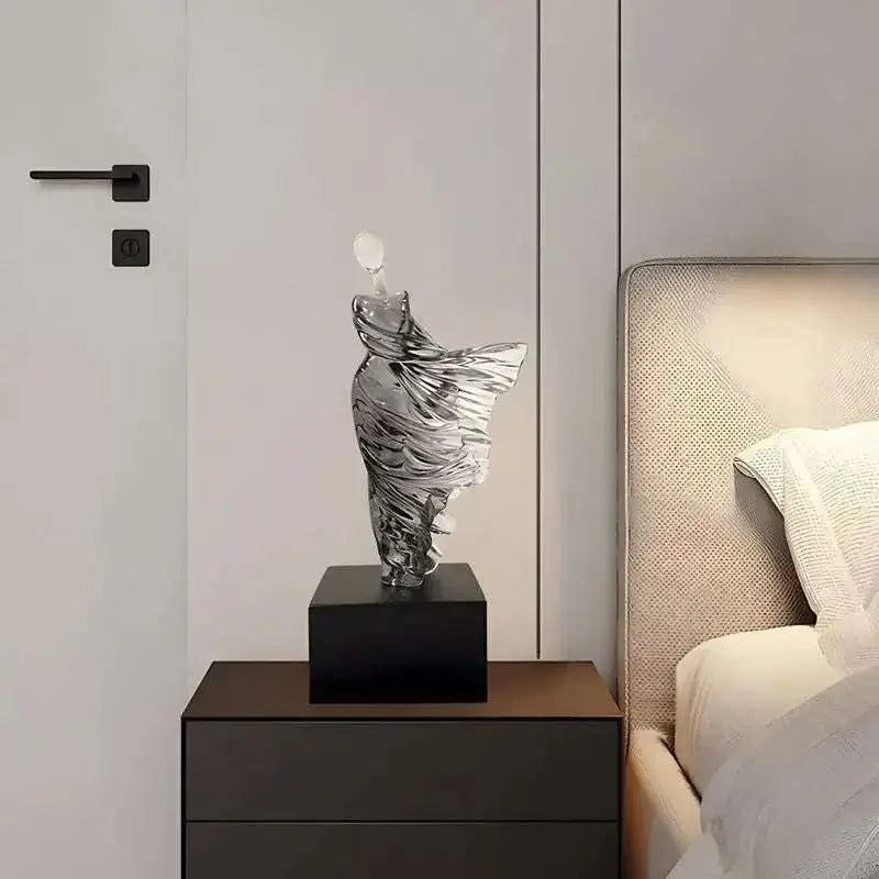 Decorative glass sculpture on a nightstand next to a bed with white bedding.