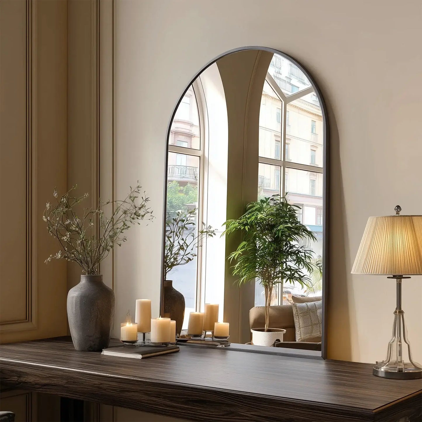 Large arched mirror on a wooden surface with decorative items in a room.