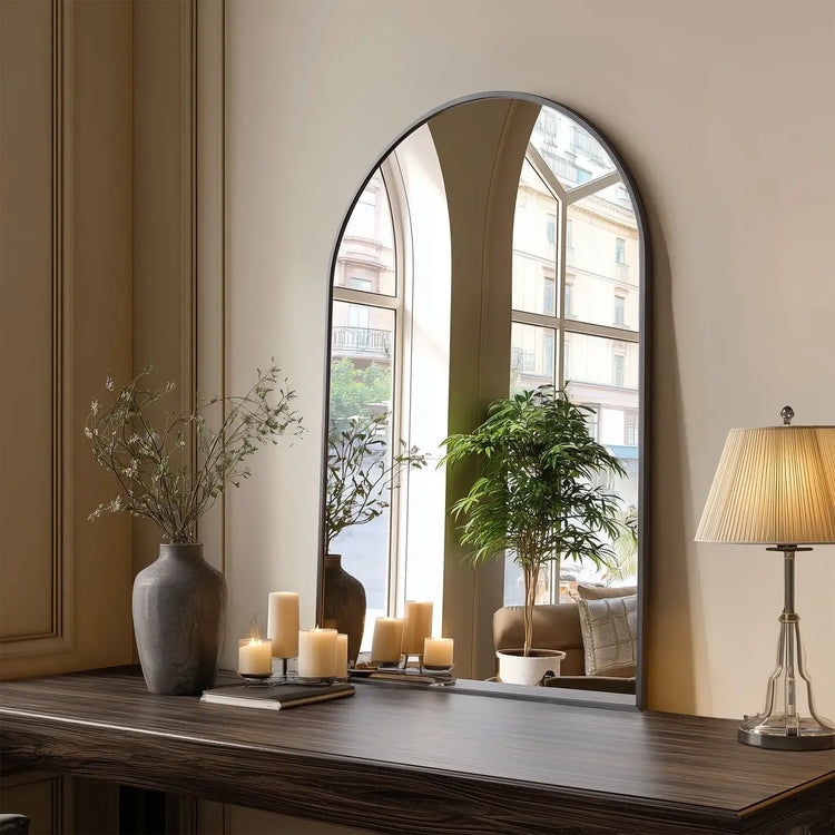 Large arched mirror on a wooden surface with decorative items in a room.