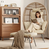 Wicker hanging chair with beige cushions next to a wooden bookshelf in a room with a lady reading a book