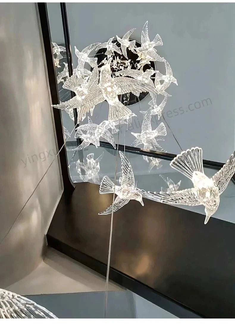 Decorative light fixture shaped like birds on a stand against a reflective surface.