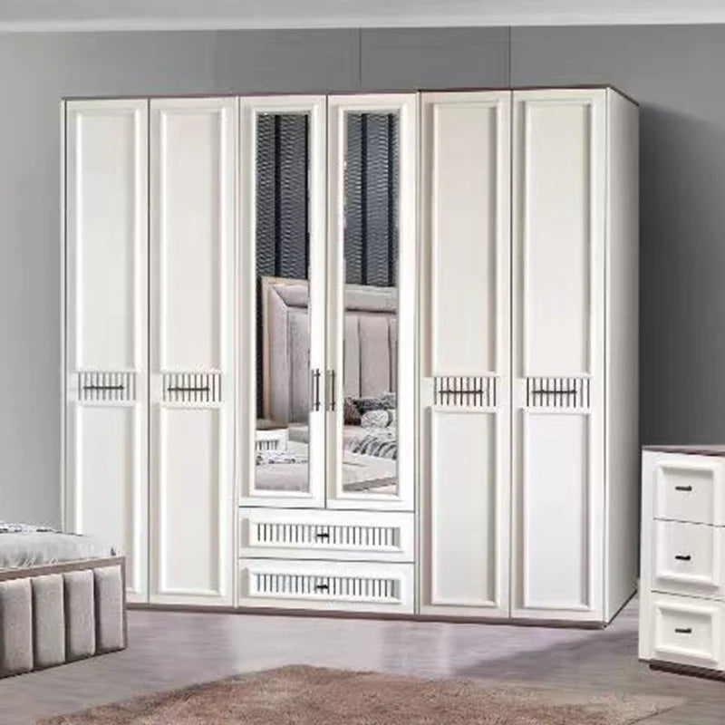 A large white wooden wardrobe with six doors, including two mirrored doors showing a bedroom reflection, set in a gray-walled bedroom next to a matching white drawer chest.