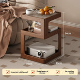Wooden side table with a projector, cup, and snacks in a living room setting. Also a patterned rug