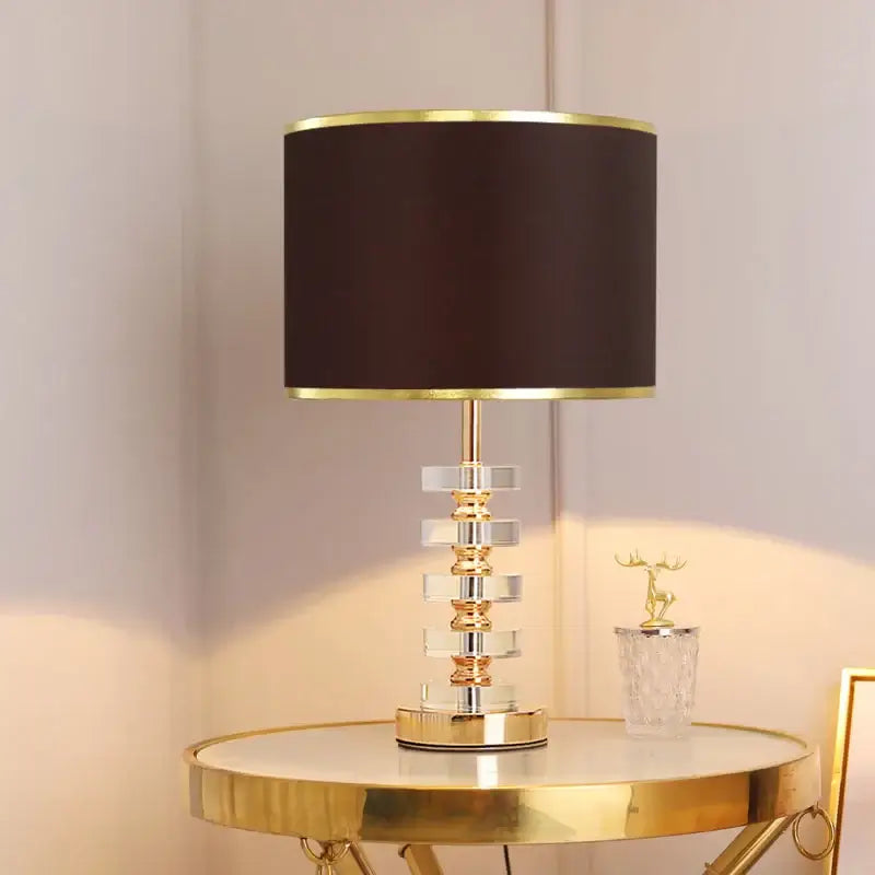 Modern crystal table lamp with fabric shade, featuring a clear crystal base and dark shade, ideal for elegant living spaces.