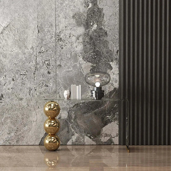 Decorative elements including a gold sculpture, black lamp, and marble-patterned wall.
