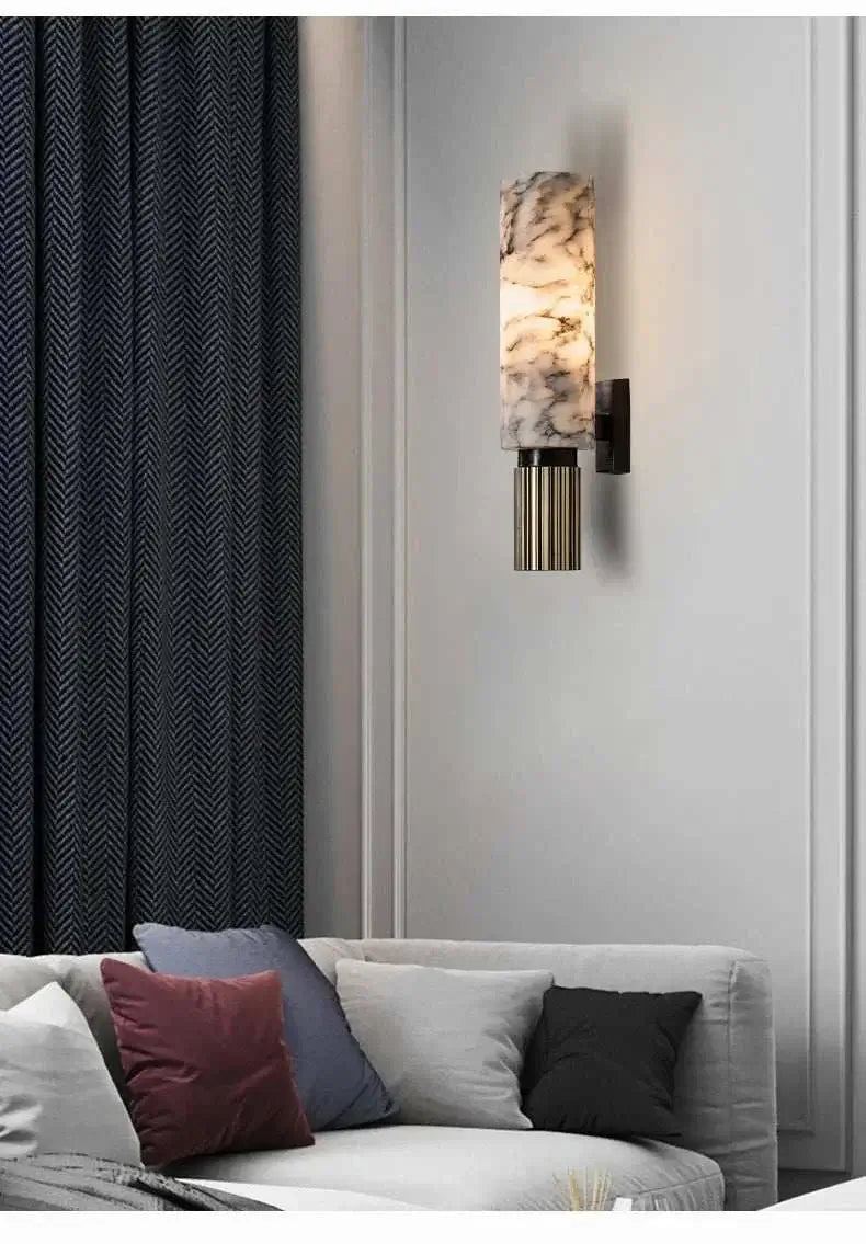 Wall-mounted lamp with marble-like design on a gray wall above a sofa with colorful cushions.