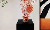 Glass sculpture on a black pedestal against a neutral background