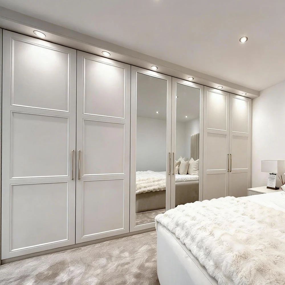 Modern bedroom with white wardrobes and a bed with white bedding.