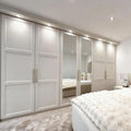 Modern bedroom with white wardrobes and a bed with white bedding.
