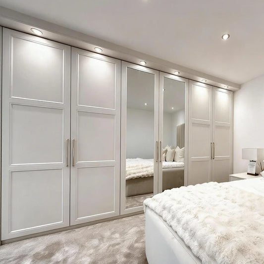 Modern bedroom with white wardrobes and a bed with white bedding.