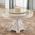Decorative round table with intricate designs in a room with patterned carpet and curtains.