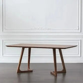Wooden dining table with a minimalist design against a white wall.