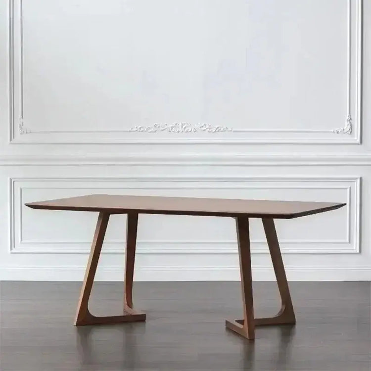 Wooden dining table with a minimalist design against a white wall.