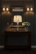 High-end crystal table lamp with fabric shade illuminating a stylish entryway with mirror and floral arrangement.