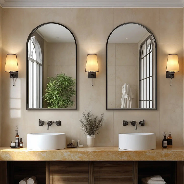 Bathroom vanity with two large arch-shaped mirrors, wall lights, and decorative items.