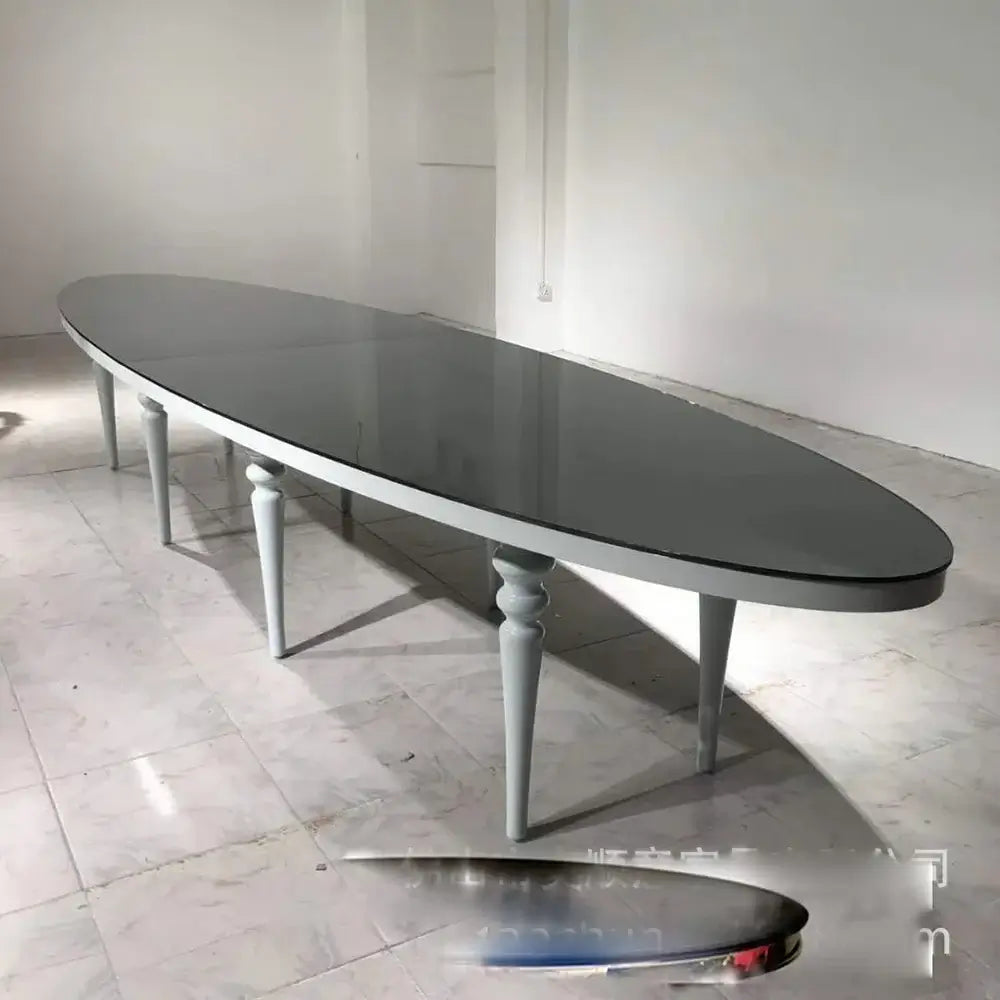 Long oval dining table with a dark surface and light gray legs in a minimalistic setting.
