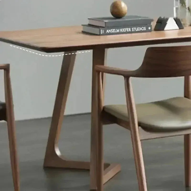 Wooden dining table with books and a decorative object on top, surrounded by chairs.