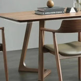 Wooden dining table with books and a decorative object on top, surrounded by chairs.