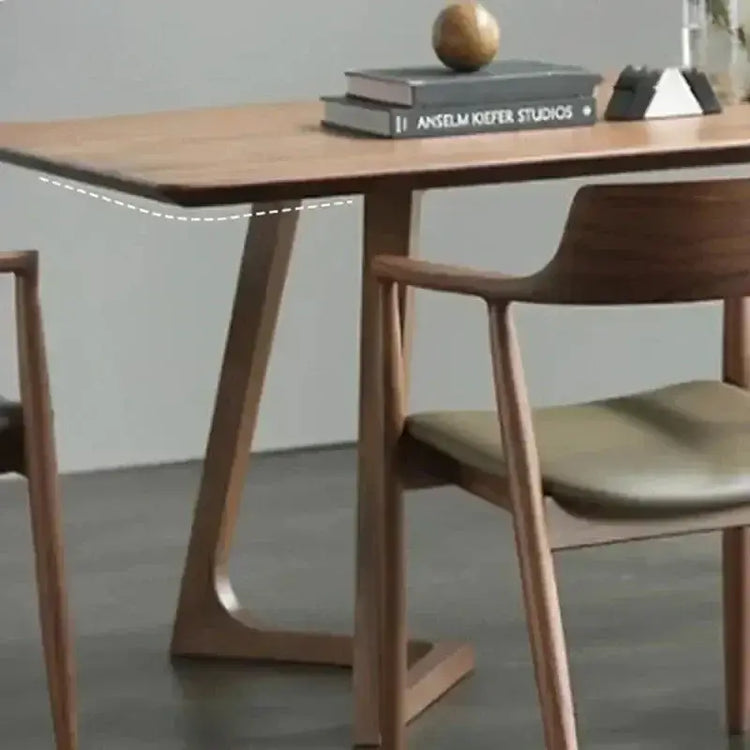 Wooden dining table with books and a decorative object on top, surrounded by chairs.