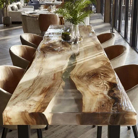 A large live-edge wooden dining table with a glossy resin finish and natural wood grain, surrounded by curved upholstered chairs in a modern dining room setting.