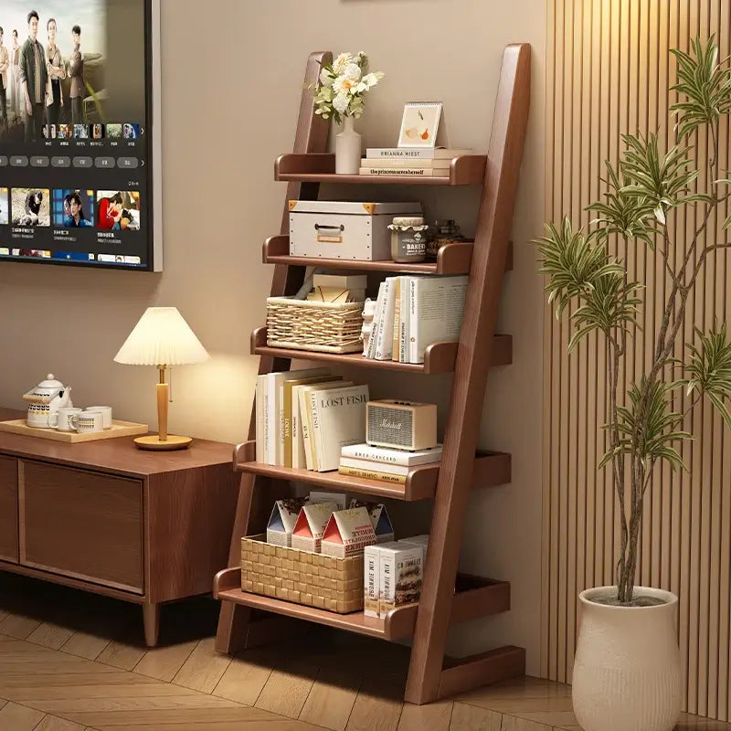 Wooden ladder shelf with books and decor in a room with a TV and desk.