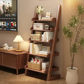 Wooden ladder shelf with books and decor in a room with a TV and desk.