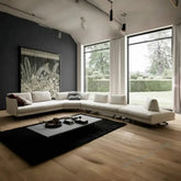 Modern living room with a large sectional sofa, coffee table, and large windows.