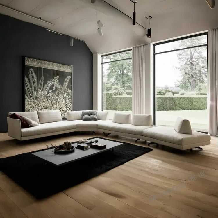 Modern living room with a large sectional sofa, coffee table, and large windows.
